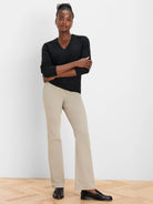 Light beige bootcut jeans on a model, subtly flared from the knee to a wide ankle opening.