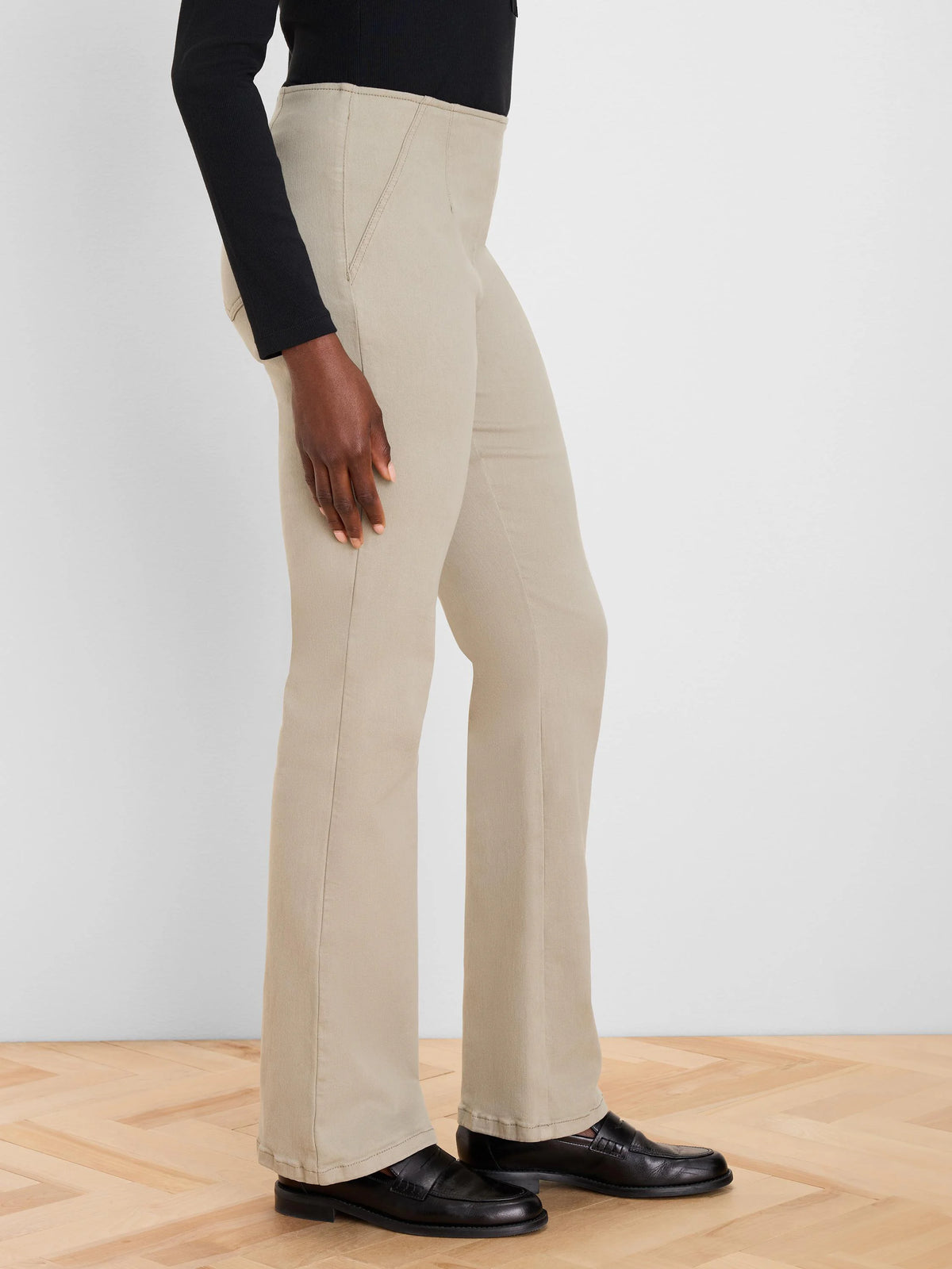 Khaki boot-cut jeans with a high waist and visible seams, worn by a model from the waist down.