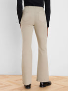 Back view of light beige high-waisted bootcut jeans with two patch pockets and flared legs.