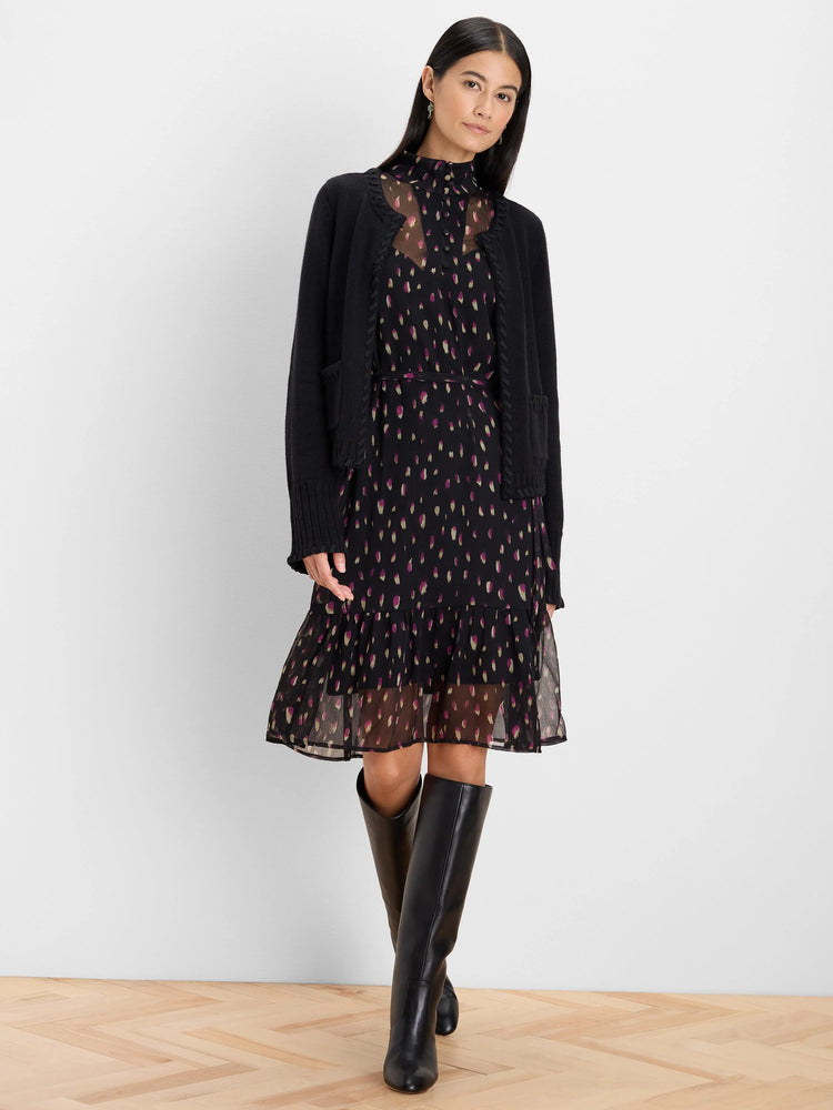 Black dress with magenta/gold petal dots. High neck, sheer bodice, cinched waist, tiered knee-length skirt.