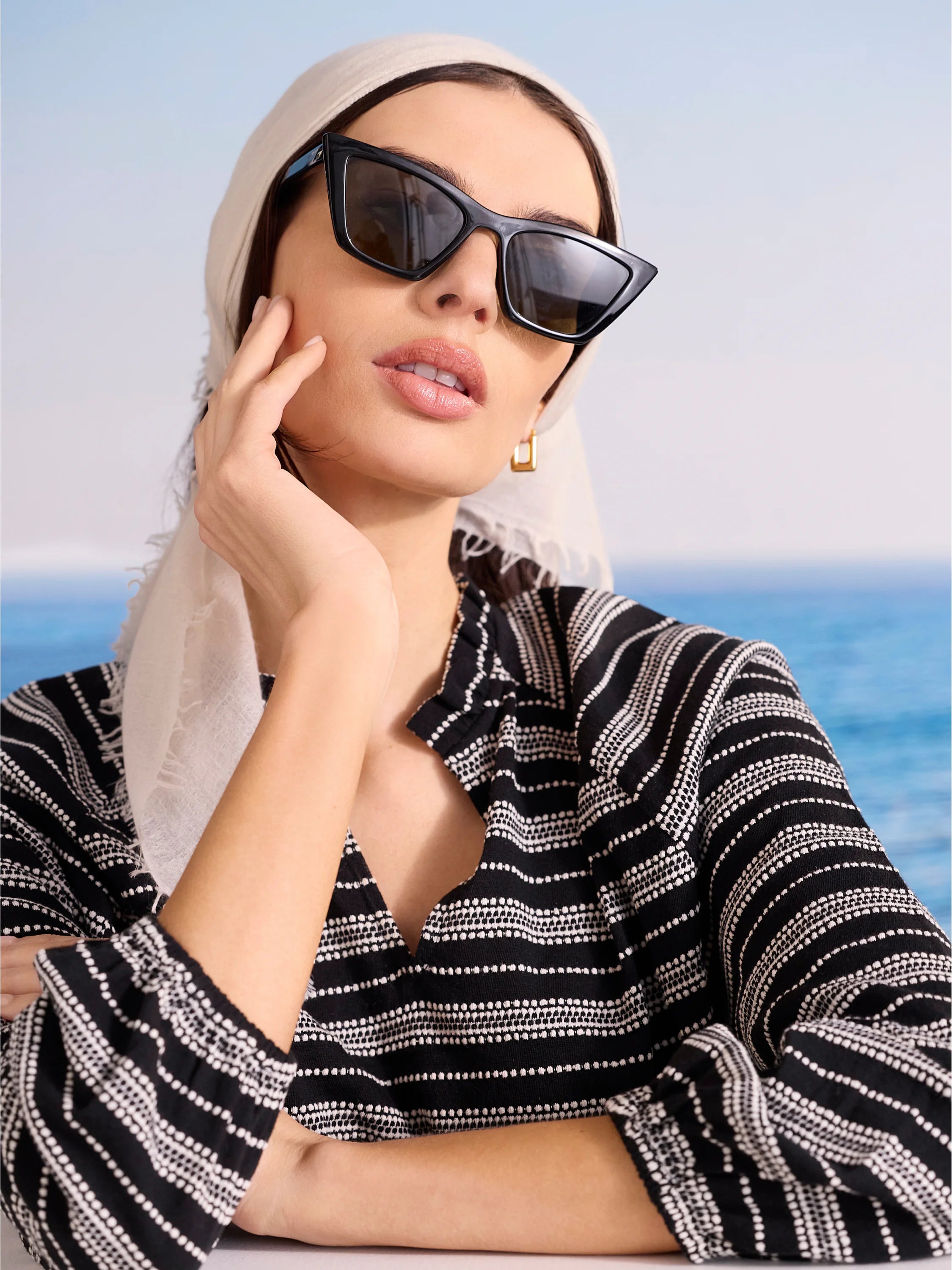 A light cream cashmere scarf, softly draped over a model's head, with fringed edges.