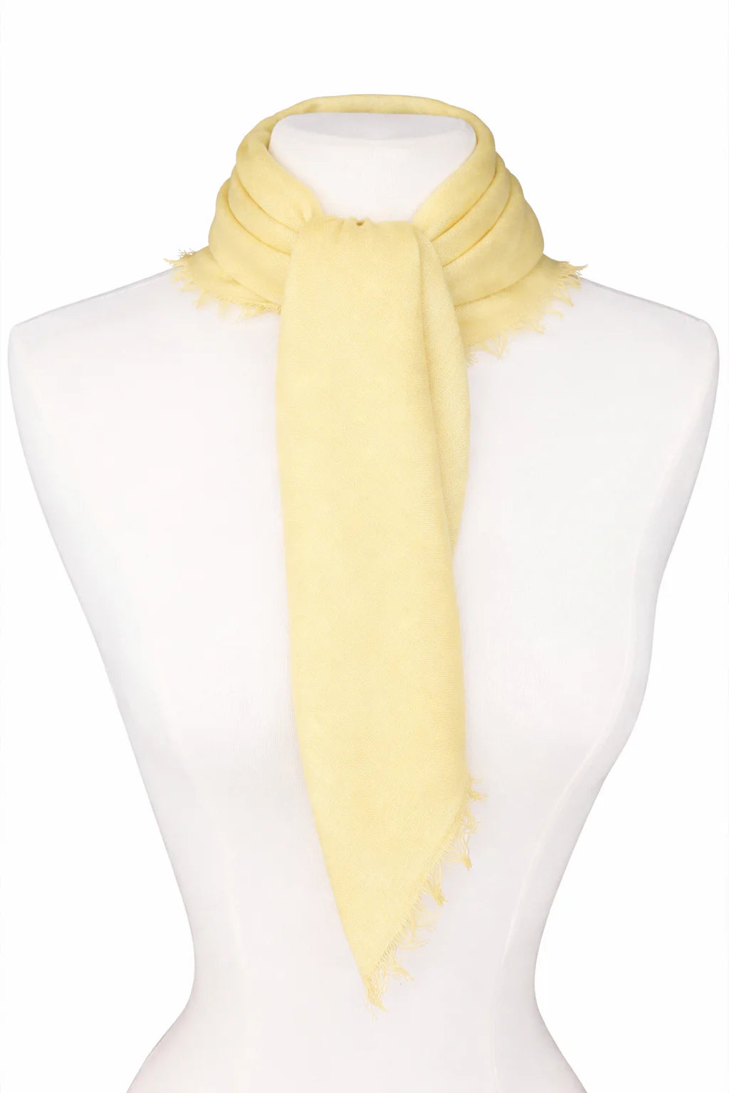 Pale yellow neck scarf tied on a mannequin with fringed edges.