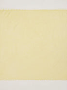 Pale yellow scarf with smooth texture and short fringed edges.