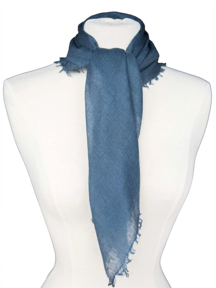 Dusty blue cashmere neck scarf with a visible weave and frayed edges, tied on a mannequin.